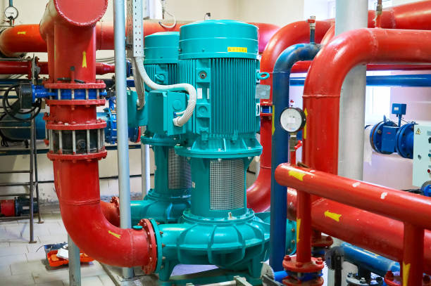 istock Two vertical engines painted blue with pumps connected to pipes painted red. 1058060100