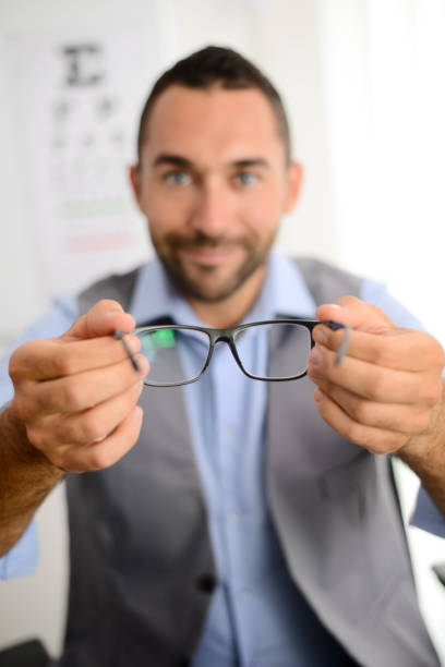 istock handsome young male optician handing optical eye glasses on white background 1058060326