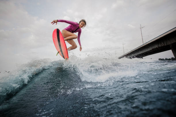 istock Active slim woman jumping up the blue wave against the grey sky 1058060564