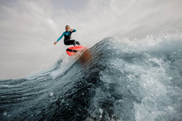 ragazzo attivo vestito con costume da bagno wakesurfing saltando su tavola arancione - wakeboarding surfing men vacations foto e immagini stock