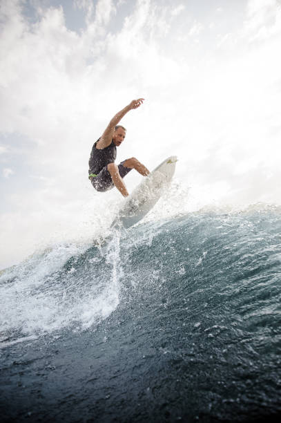istock Man jumping on the white wakeboard down the blue water against grey sky 1058061244