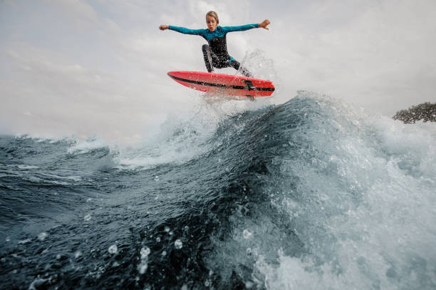 istock Active child boy dressed in swimsuit wakesurfing jumping up on orange board 1058061316