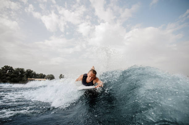 istock Handsome wakesurfer lying on white board and swimming down the river 1058061810