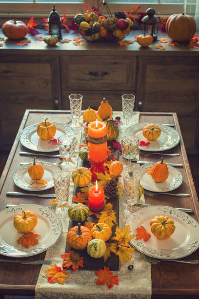Autumn table setting for Thanksgiving dinner with candles, pumpkins and leafs