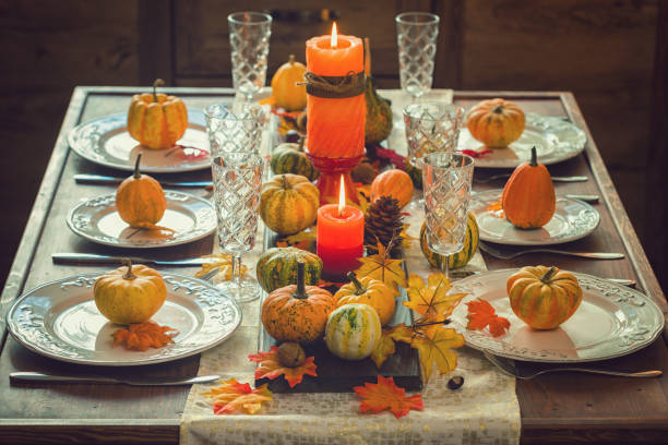 Autumn table setting for Thanksgiving dinner with candles, pumpkins and leafs