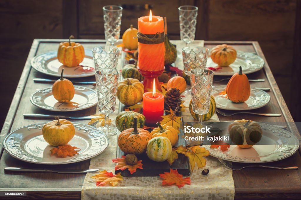 Thanksgiving Dining Table Place Setting with Autumn Decoration Autumn table setting for Thanksgiving dinner with candles, pumpkins and leafs Thanksgiving - Holiday Stock Photo