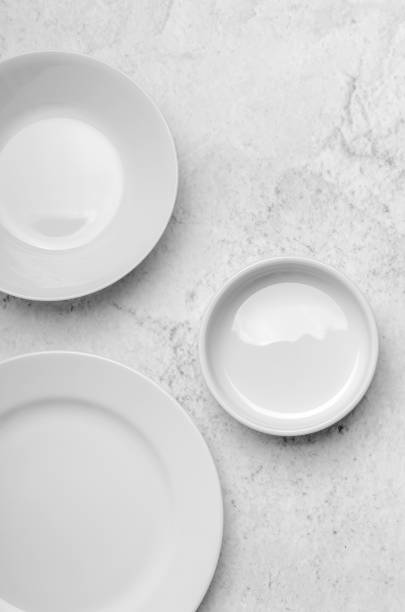 istock A clean little white plates on light stone background. Minimalistic kitchen, dishes. Top view, flat lay 1058085322