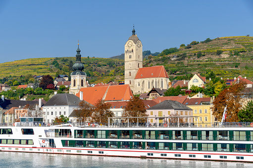 cruising ship at the landing stage of Krems/Stein with Frauenberg church, St. Nicholas church and vineyard hills in the background, Krems, Austria