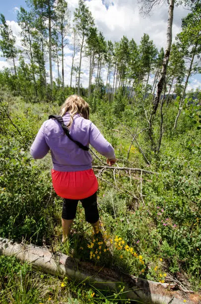 Cautious woman tries to hike in the wilderness wearing the wrong gear and clothing, only flip flops and capri pants