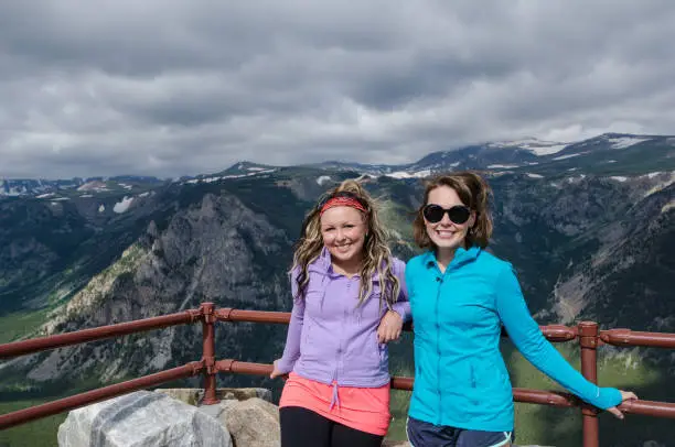 Two female friends pose together at an overlook along Montana Beartooth Pass Highway in the Rocky Mountains