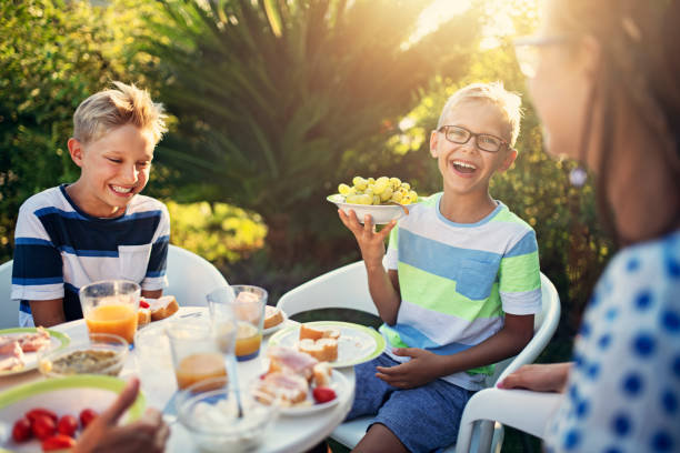 幸せな子供の食べる新鮮な朝食屋外 - family grape ストック��フォトと画像