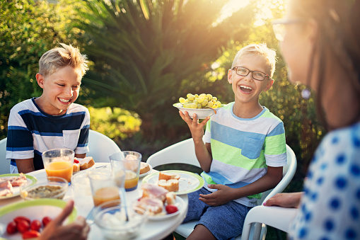 Three kids having fun eating fresh breakfast in the garden.
Nikon D850