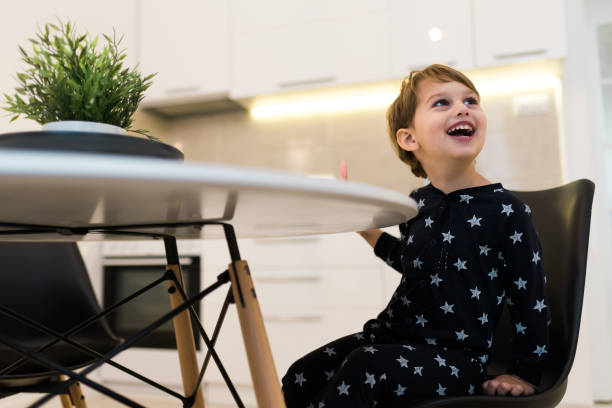 istock Happy kid sitting at the kitchen table and eating 1058111792