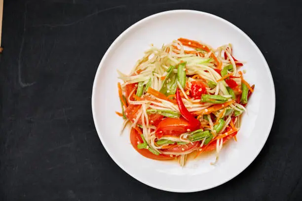 Thai food "Som tum" or green papaya salad mixed with Thai traditional ingredient and sauce with red chili, tomato, long bean, carrot. Famous spicy food of Thailand.