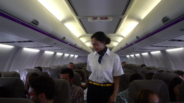 Beautiful black flight attendant checking everyone os wearing their seatbelts before take off