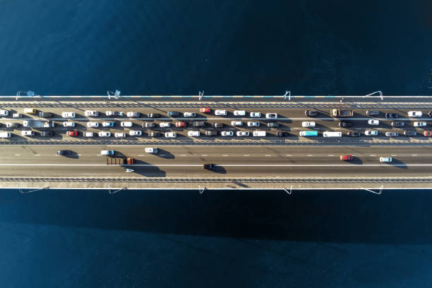 aerial view of road bridge across river with heavy traffic jam in one direction. rush hour with mash and overloading of road infrastructure. resolving of car traffic jam - road top view imagens e fotografias de stock