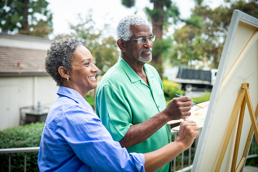 An attractive senior black couple painting in nature