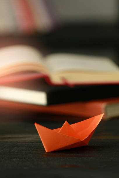 istock Paper Boat At Edge Of Book 1058128668