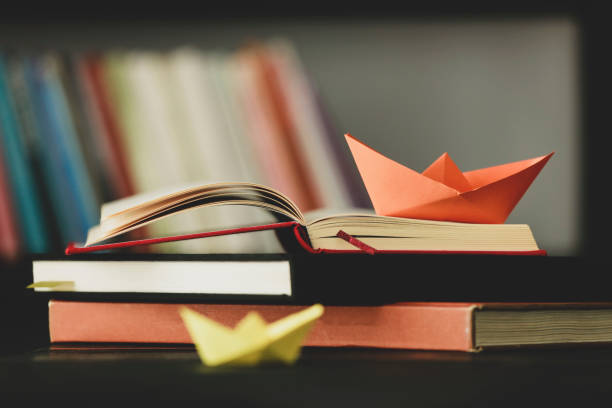 istock Paper Boat At Edge Of Book 1058128682