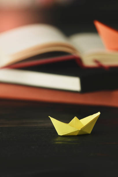 istock Paper Boat At Edge Of Book 1058128748