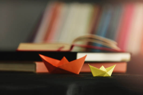 istock Paper Boat At Edge Of Book 1058128804