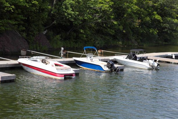 The river tug o floats on the river against the background of the shore overgrown with trees and shrubs, leaving behind traces of foam.