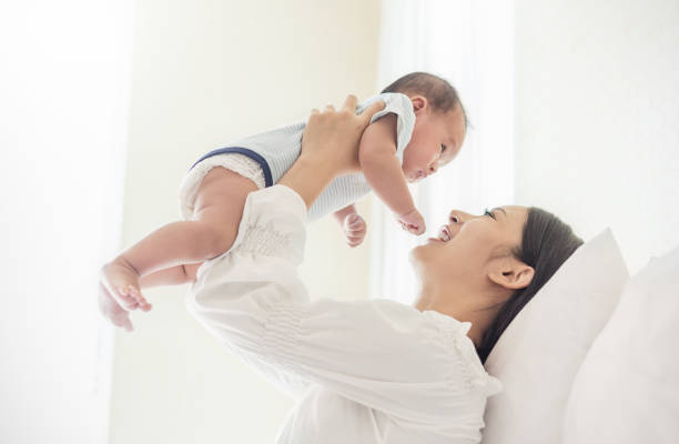 retrato de mãe levantar e brincar com o bebê recém-nascido, bebê, falar com a mãe. cuidados de saúde familiar amor junto - japanese ethnicity women asian and indian ethnicities smiling - fotografias e filmes do acervo