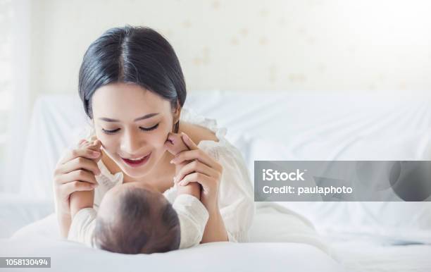 Happy Asian Mother Playing With Newborn Baby Baby Talking To Mother Lifestyle Mothers Day Nursery Concept Stock Photo - Download Image Now