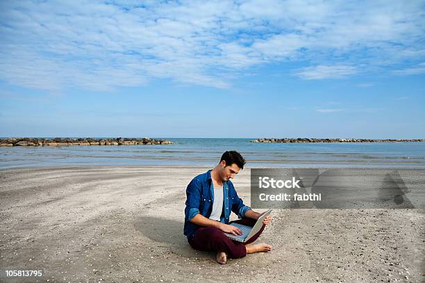 Jovem Sentado Na Praia Com O Computador Portátil - Fotografias de stock e mais imagens de 20-24 Anos - 20-24 Anos, 20-29 Anos, 25-29 Anos