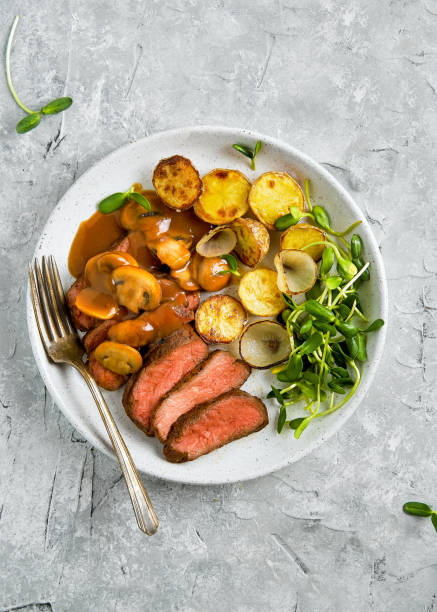 istock Medium rare steak with roasted potatoes and mushroom gravy 1058140084