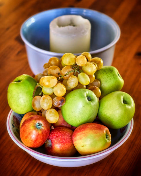 bowl of apples and grapes with candle on wooden table