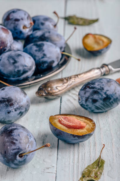 istock Plums with leaves and knife over wooden surface 1058152040