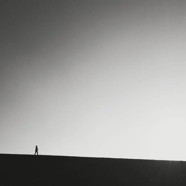 istock silhouette of a man walking down a hill, clean sky 1058155982