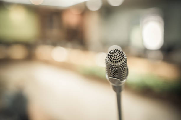 istock Front Microphone on abstract conference hall prepare for speaker on stage in seminar room, Business meeting and education in teaching classroom or Event light convention hall Background. 1058161190