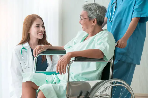 asian attractive woman doctor and nurse takecare old senior patient disabled on wheelchair in hospital health and support ideas concept