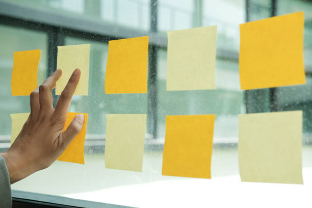 istock hand touch on adhesive notes on glass wall. Sticky note paper reminder schedule for creative idea & business brainstorming 1058161468