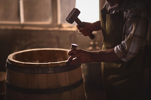 the master makes a wooden barrel for brandy, oak boards compresses them with iron rings