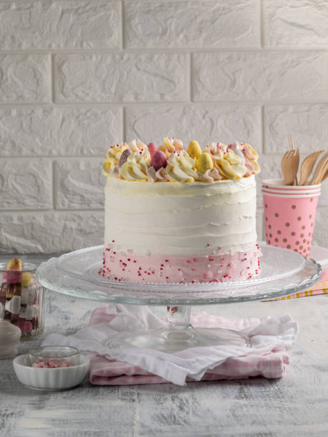 istock Colorful Birthday cake with sprinkles and mini eggs on a light background. Vertical. Copy space. 1058165304