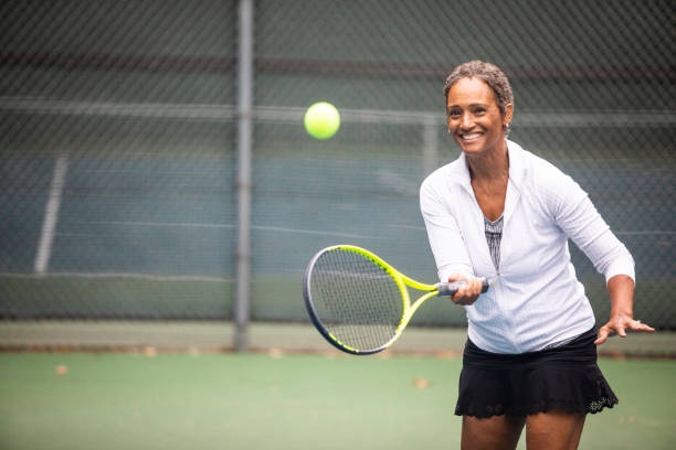 beautiful senior black woman playing tennis - womens tennis imagens e fotografias de stock