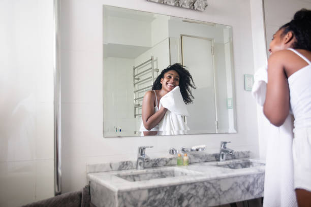 Beautiful black woman drying her face with a towel while looking at herself in the mirror smiling Beautiful black woman drying her face with a towel  in the bathroom while looking at herself in the mirror smiling woman washing face stock pictures, royalty-free photos & images