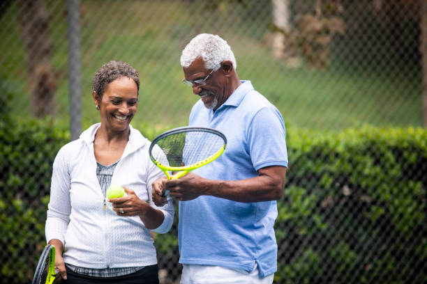 älteres schwarzes paar auf tennisplatz - tennis active seniors healthy lifestyle senior men stock-fotos und bilder