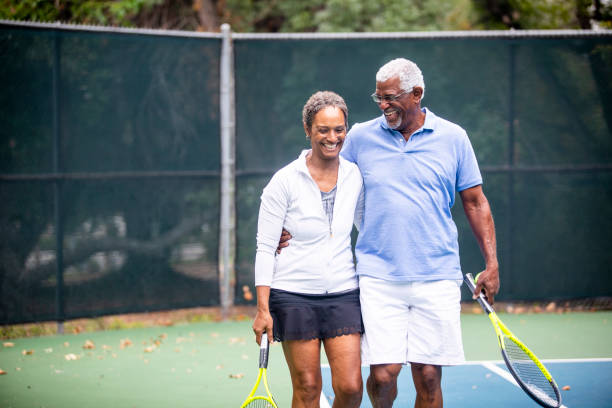 älteres schwarzes paar auf tennisplatz - tennis active seniors healthy lifestyle senior men stock-fotos und bilder