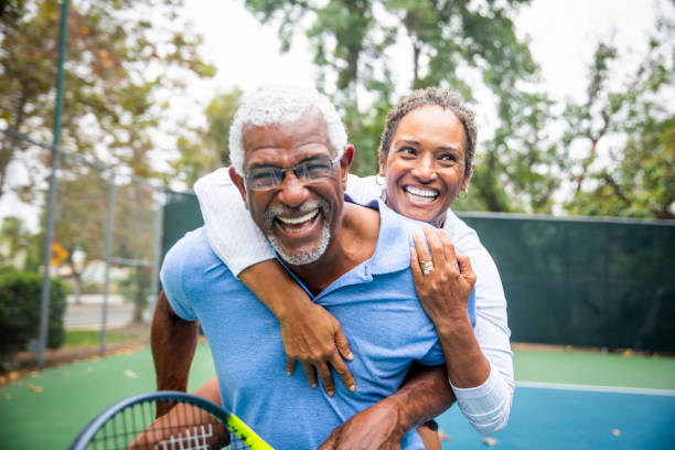 senior pareja negro tenis piggyback - tennis couple women men fotografías e imágenes de stock
