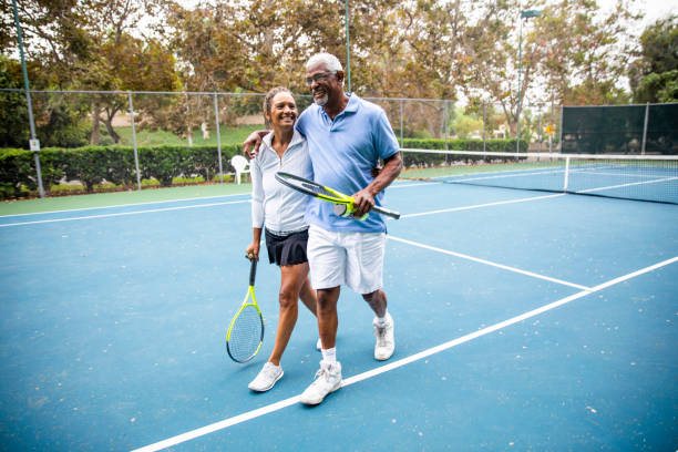 senior pareja negro caminando fuera de la cancha de tenis - senior adult african descent men african ethnicity fotografías e imágenes de stock