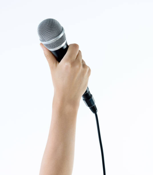 istock Woman hand holding a microphone on white background 1058186576