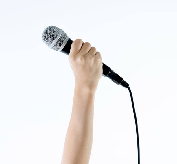 istock Woman hand holding a microphone on white background 1058186598