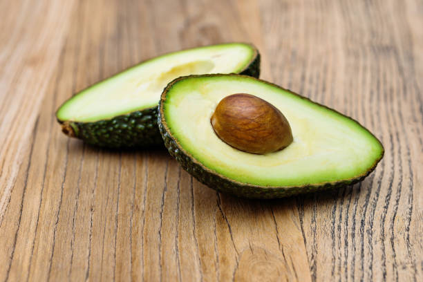 istock Two halves of avocado on wooden table 1058187700