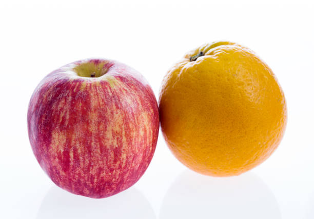 manzana roja y naranja sobre fondo blanco - comparison apple orange isolated fotografías e imágenes de stock