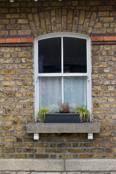 istock White arched window with a flower box within a light brown brick wall background 1058188262