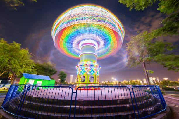 回転照らされた魅力観覧車とメリーゴーランド メリーゴーランド夏の夜市遊園。 - ferris wheel wheel blurred motion amusement park ストックフォトと画像